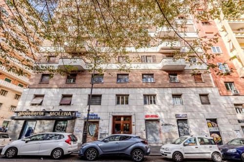 Facciata a livello strada dell'Amor Rome Apartment a Roma, Italia con edificio storico e auto parcheggiate