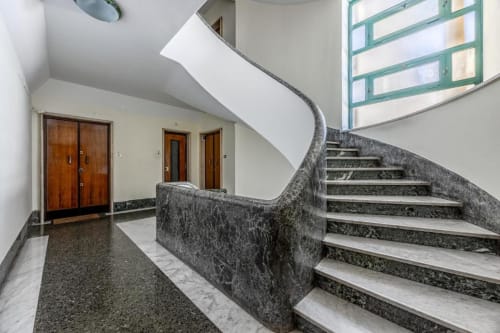 Scala moderna con ringhiera in marmo nella hall dell'Amor Rome Apartment, con porte in legno e luce naturale