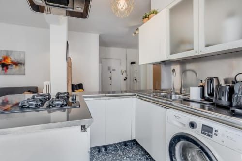 Cucina bianca moderna nell'Appartamento Amor Roma con fornello, lavatrice e elettrodomestici in acciaio inossidabile