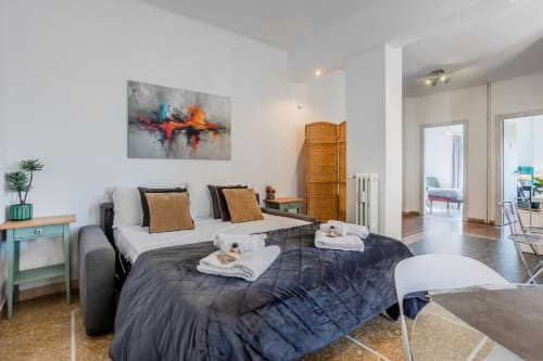 Camera moderna dell'Amor Rome Apartment con letto, arte astratta colorata, scrivania turchese e layout aperto a Roma