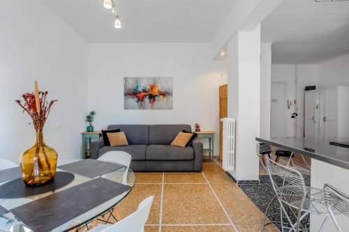 Zona living di moderno appartamento romano con divano grigio, tavolo da pranzo e cucina all'Amor Rome Apartment