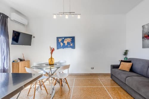 Luminoso appartamento romano con tavolo da pranzo, divano grigio, mappamondo e arredi contemporanei in spazio bianco