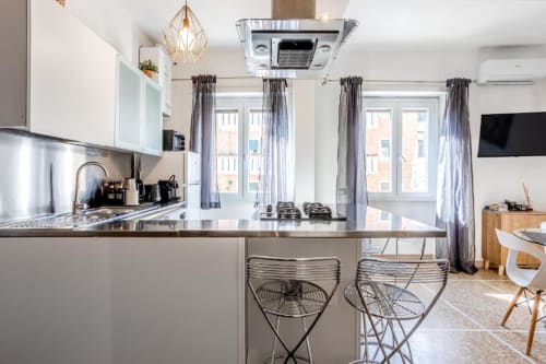 Cucina moderna con isola e posti a sedere presso l'Amor Rome Apartment, dotata di elettrodomestici in acciaio inossidabile e luce naturale