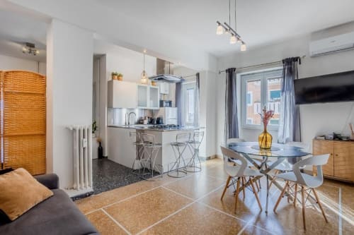 Moderno appartamento a Roma con cucina a vista, tavolo da pranzo e zona living arredata in stile contemporaneo