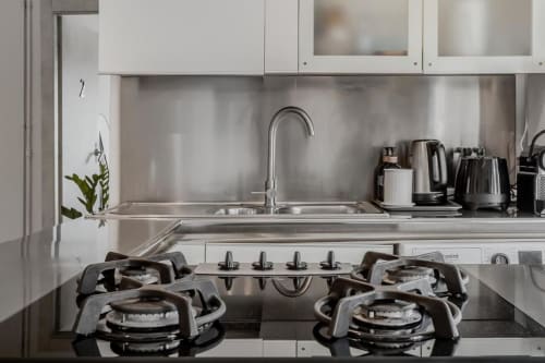 Cucina moderna dell'Amor Rome Apartment con piano cottura a gas in acciaio inossidabile, lavello e mobili bianchi