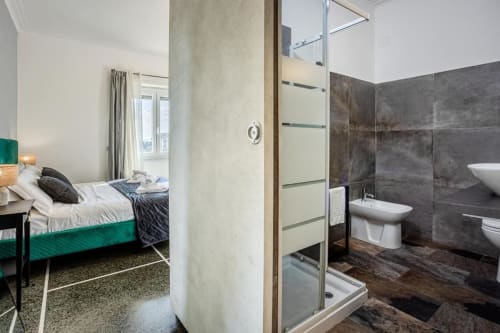 Camera da letto moderna con bagno ensuite all'Amor Rome Apartment: letto verde, doccia in piastrelle scure e design contemporaneo