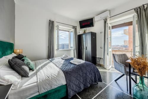 Camera da letto moderna a Roma con testata verde, balconi con vista città, TV Netflix e arredi contemporanei