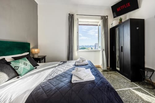Camera da letto moderna presso Amor Rome Apartment con testata in velluto verde, vista sulla città, TV con Netflix e armadio nero a Roma