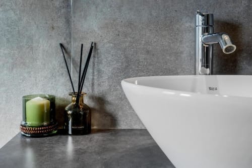 Lavabo moderno Roca bianco con rubinetto cromato, candela verde e diffusore di palo santo nell'appartamento di Roma