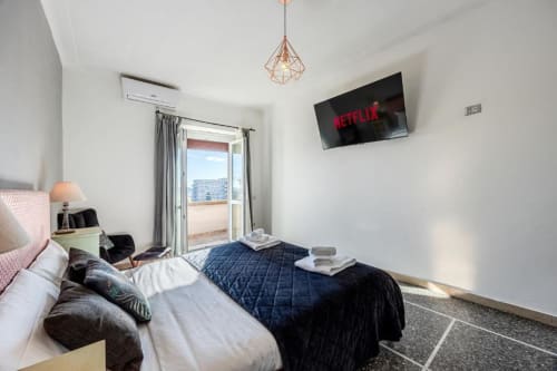Camera moderna dell'Amor Rome Apartment con letti gemelli, TV a parete, balcone con vista sulla città e lampada a sospensione geometrica