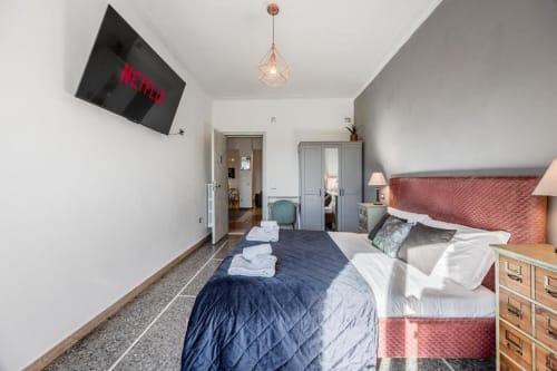 Camera da letto moderna dell'Amor Rome Apartment a Roma con letto matrimoniale, TV Netflix a parete, lampada a sospensione e arredamento contemporaneo