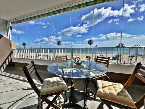 Terraza con vista al mar, paredes de cristal y mesa de comedor en Fuengirola, España