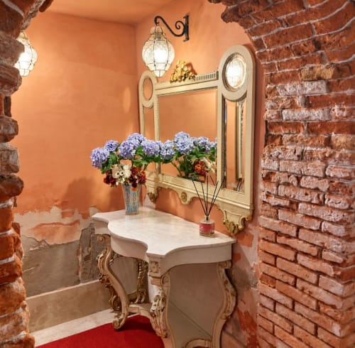 Elegante lavabo con consolle in crema, specchio decorativo e ortensie blu nel Palazzo Titti di Venezia