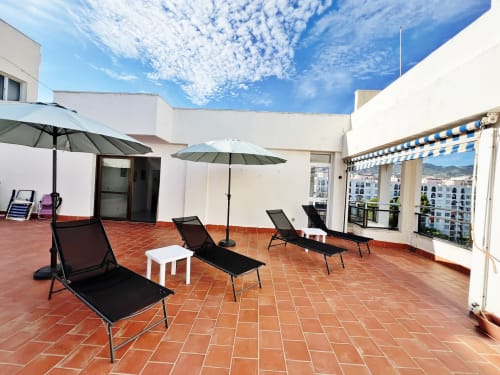 Terraza en azotea con tumbonas, sombrillas y toldo azul y blanco en Fuengirola
