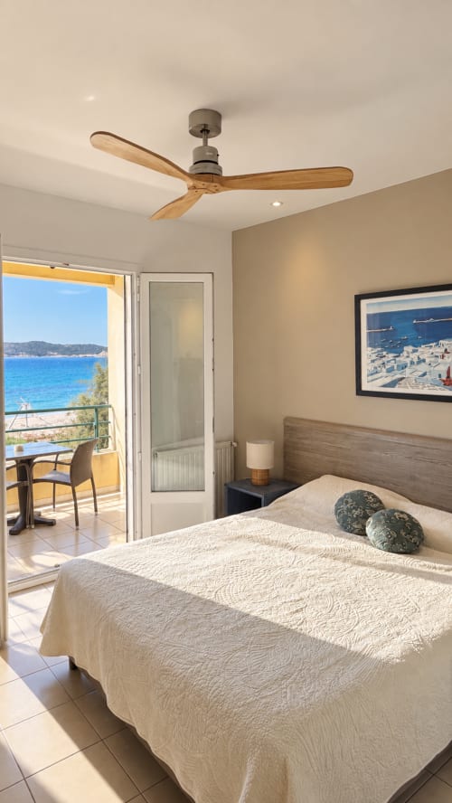 Chambre côtière à l'Hôtel Thalassa à Cargèse avec vue sur mer, ventilateur de plafond en bois et balcon dominant la Méditerranée bleue