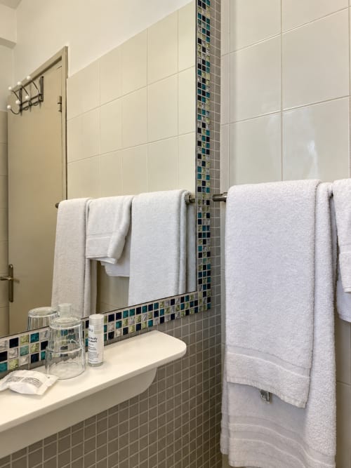 Salle de bain moderne à l'Hôtel Thalassa à Cargèse avec serviettes blanches, carrelage décoratif et équipements de toilette