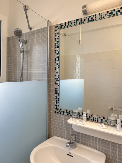 Salle de bain moderne à l'Hôtel Thalassa à Cargèse avec douche carrelée, accents de mosaïque et miroir de vanité