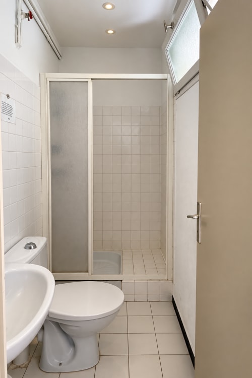 Salle de bain moderne avec toilettes, cabine de douche et carrelage blanc à l'Hôtel Thalassa à Cargèse