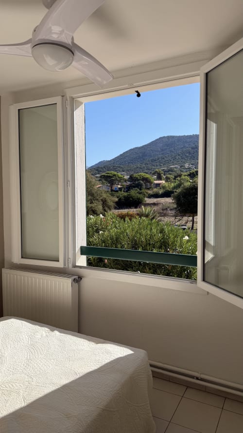 Chambre avec fenêtre ouverte surplombant la campagne à l'Hôtel Thalassa, Cargèse, vue sur les montagnes et le village