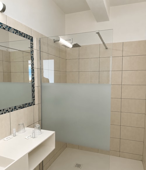 Salle de bain moderne à l'Hôtel Thalassa, Cargèse, avec carrelage beige, paroi vitrée, douchette pluie et lavabo
