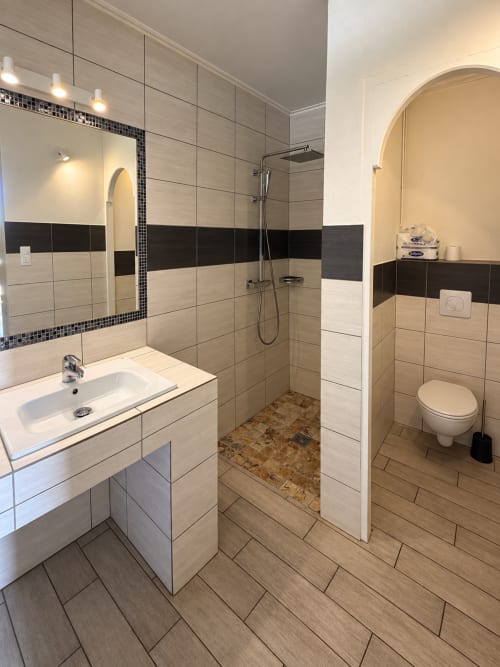 Salle de bain moderne de l'Hôtel Thalassa Cargèse avec douche carrelée, lavabo, toilettes et sol chauffant