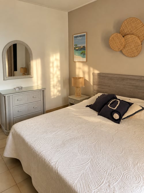 Chambre lumineuse et aérée à l'Hôtel Thalassa à Cargèse, avec literie crème, touches tissées et décor côtier