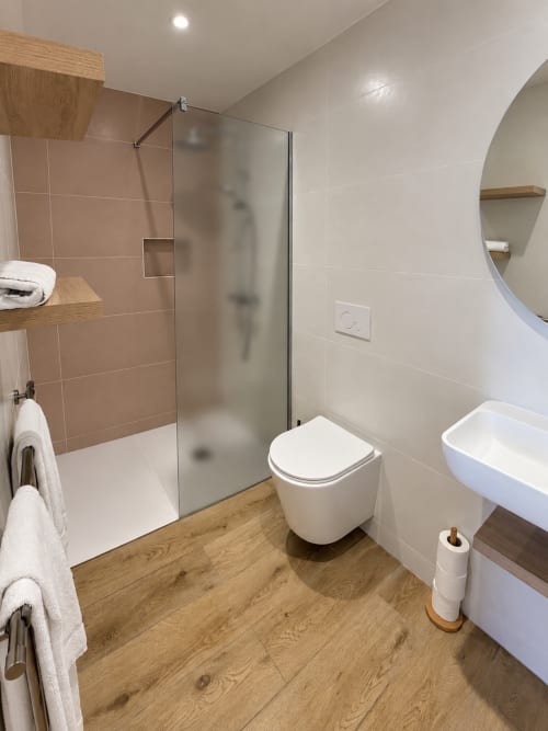 Salle de bain moderne de l'Hôtel Thalassa Cargèse avec douche vitrée, toilettes murales, parquet et équipements blancs