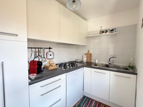 Cucina moderna bianca con piano cottura a gas, top nero e lavello in acciaio inox nell'appartamento La Sorgente a Roseto del