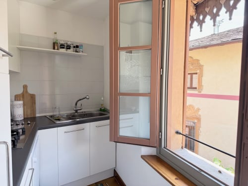 Cucina compatta nell'appartamento La Sorgente a Roseto del Drago con mobili bianchi, piano nero e finestra con vista
