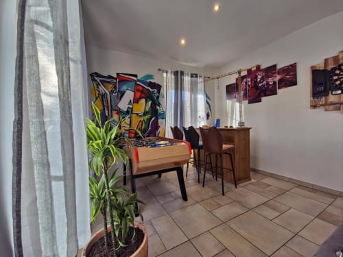 Espace de vie moderne aux Tanneries à Ornans avec baby-foot coloré, bureau et plante en pot
