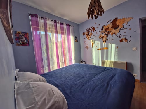 Chambre lumineuse aux Tanneries d'Ornans avec literie bleue, rideaux à rayures roses et carte du monde en bois