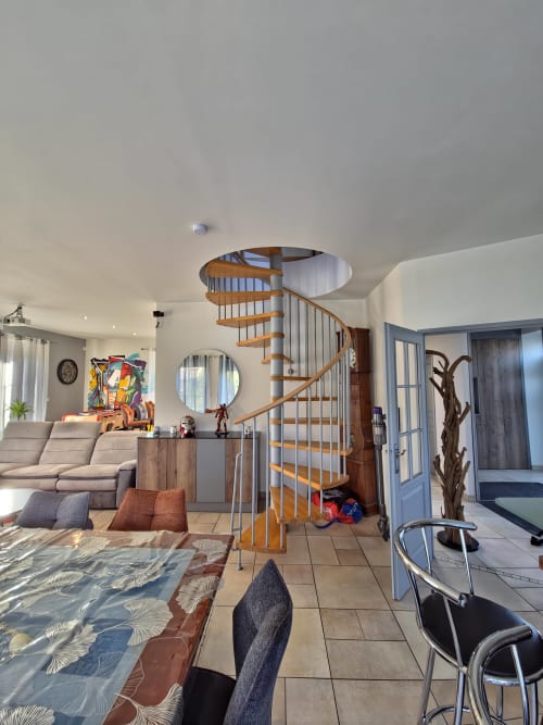 Appartement moderne ouvert aux Tanneries d'Ornans avec escalier hélicoïdal, salon avec canapé et vue sur la rivière