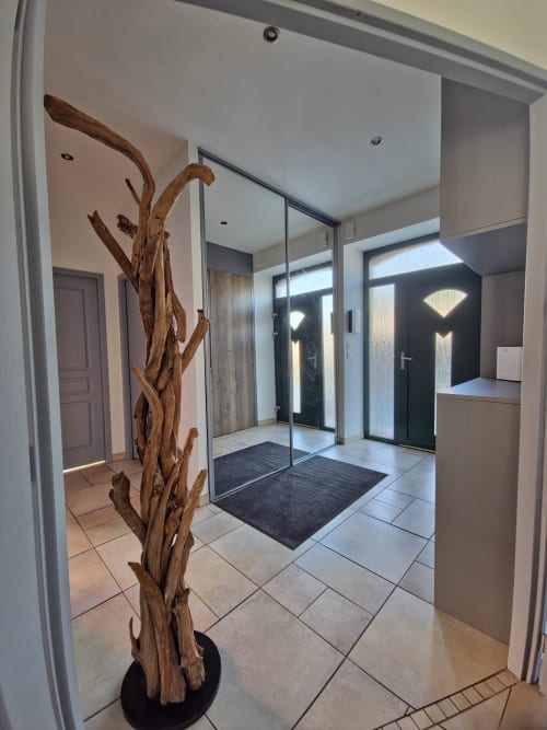 Entrée contemporaine des Tanneries Ornans avec sculpture bois, porte vitrée et carrelage menant à appartement vue rivière