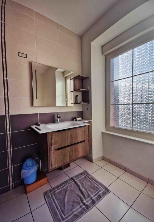Salle de bain moderne de l'appartement Maison les pieds dans l'eau aux Tanneries B&B, Ornans, avec vasque en bois et carrelage foncé