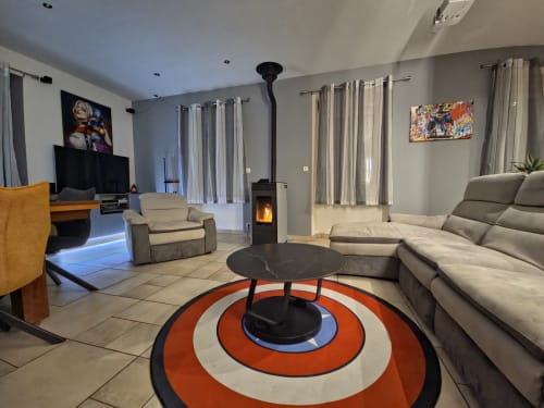Salon moderne avec canapé beige, cheminée et tapis géométrique orange à l'appartement Les Tanneries à Ornans