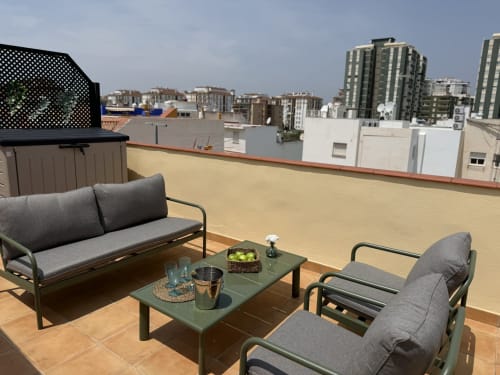 Terraza en la azotea de Fuengirola con zona de descanso, mesa verde y vistas del horizonte de la ciudad