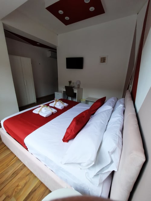 Camera moderna presso U Baruni b&b a Messina con accenti rossi, TV a schermo piatto, pavimenti in legno e vista sulla città