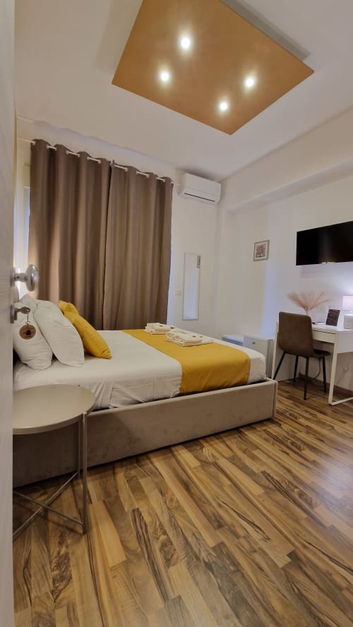 Moderna camera matrimoniale all'U Baruni b&b di Messina con accenti gialli, TV schermo piatto, aria condizionata e pavimenti in legno