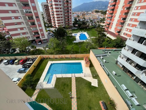 Vista aérea del complejo residencial Grupo Inmohouse en Fuengirola con piscinas, jardines y edificios de apartamentos rojo y blanco