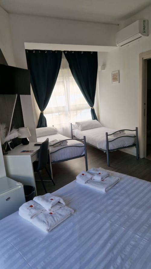 Spaziosa camera familiare presso U Baruni b&b a Messina con più letti, tende nere, aria condizionata, scrivania e vista sulla città