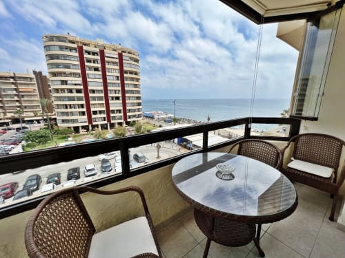 Balcón frente al mar con vistas al océano, zona de estar y edificios costeros en Fuengirola