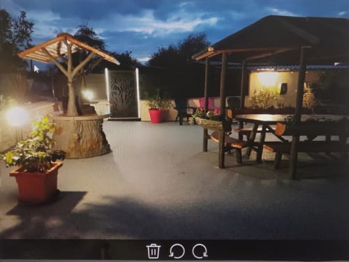 Chez Mariebel's illuminated garden courtyard at dusk with wooden pergolas, seating areas, and potted plants in Ottonville