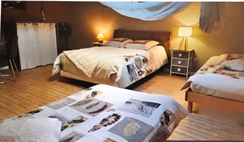Cozy bedroom at Chez Mariebel' cottage in Ottonville with two beds, warm lighting, and feather artwork display