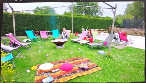 Colorful garden gathering space at Chez Mariebel with loungers, fire pit, and blankets on grass