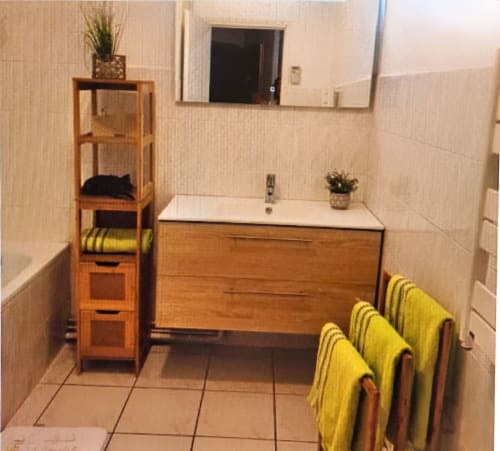 Modern bathroom at Chez Mariebel' cottage in Ottonville with wooden vanity, mirror, and yellow towels