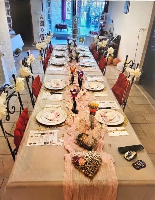 Elegant dining table setup at Chez Mariebel' cottage in Ottonville with red chairs, white place settings, and floral