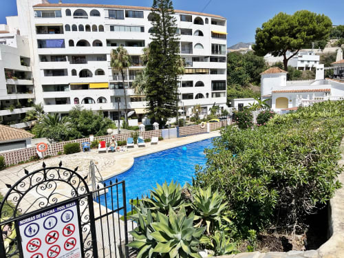 Piscina del complejo de Fuengirola con modernos edificios de apartamentos blancos y paisajismo mediterráneo
