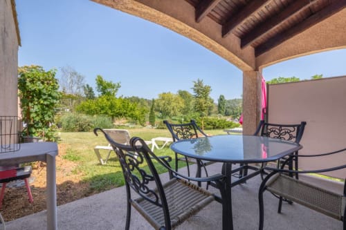 Covered patio with dining table and chairs overlooking garden at Domaine de la Bégude, Fayence