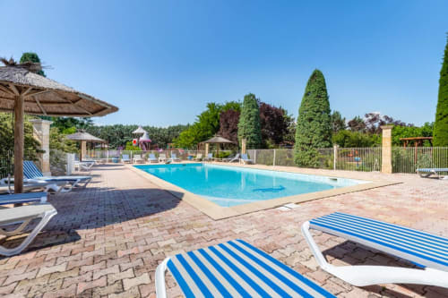 Piscine de villégiature avec transats bleus au Domaine de la Bégude à Fayence, entourée de paysages soignés et ciel dégagé