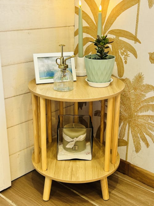 Table basse ronde en bois à La Bounty, La Villa Plein Vent, décorée d'une plante, bougies et photo encadrée